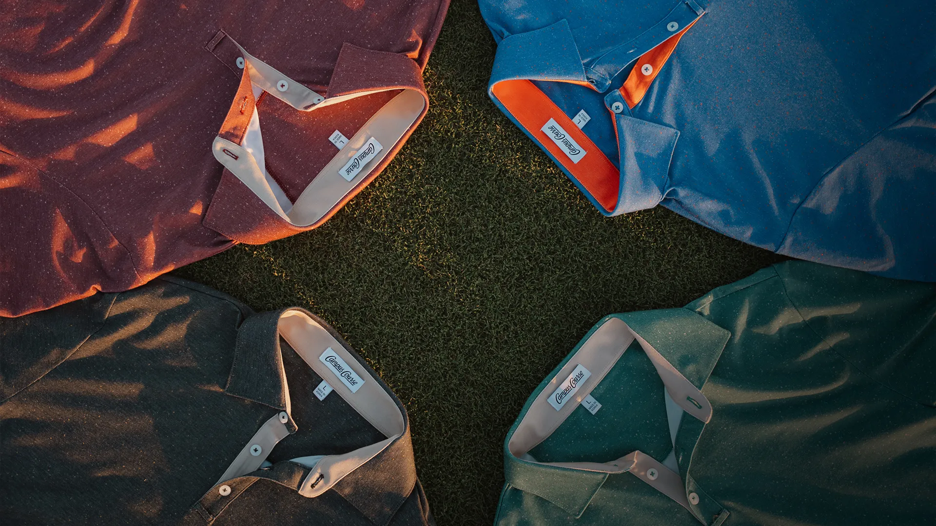 Four Campus Course polos laid collar to collar on golf course grass at sunset